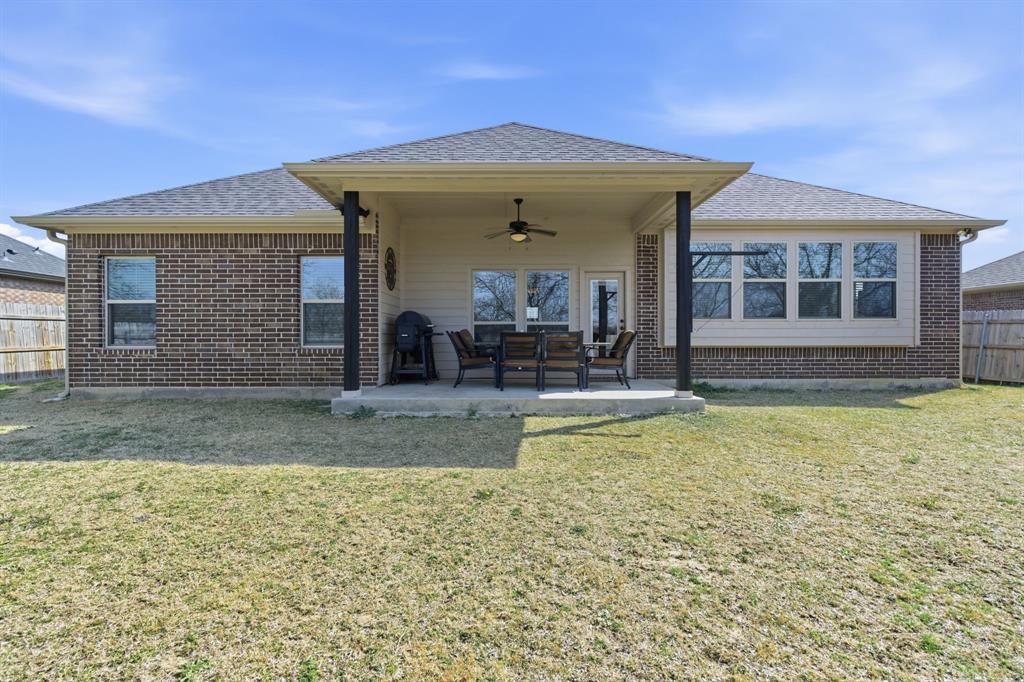 711 Hadley Lane Valley View, TX 76272 - Photo 29 of 40 Back of property with ceiling fan, a patio area, a shingled roof, and brick siding