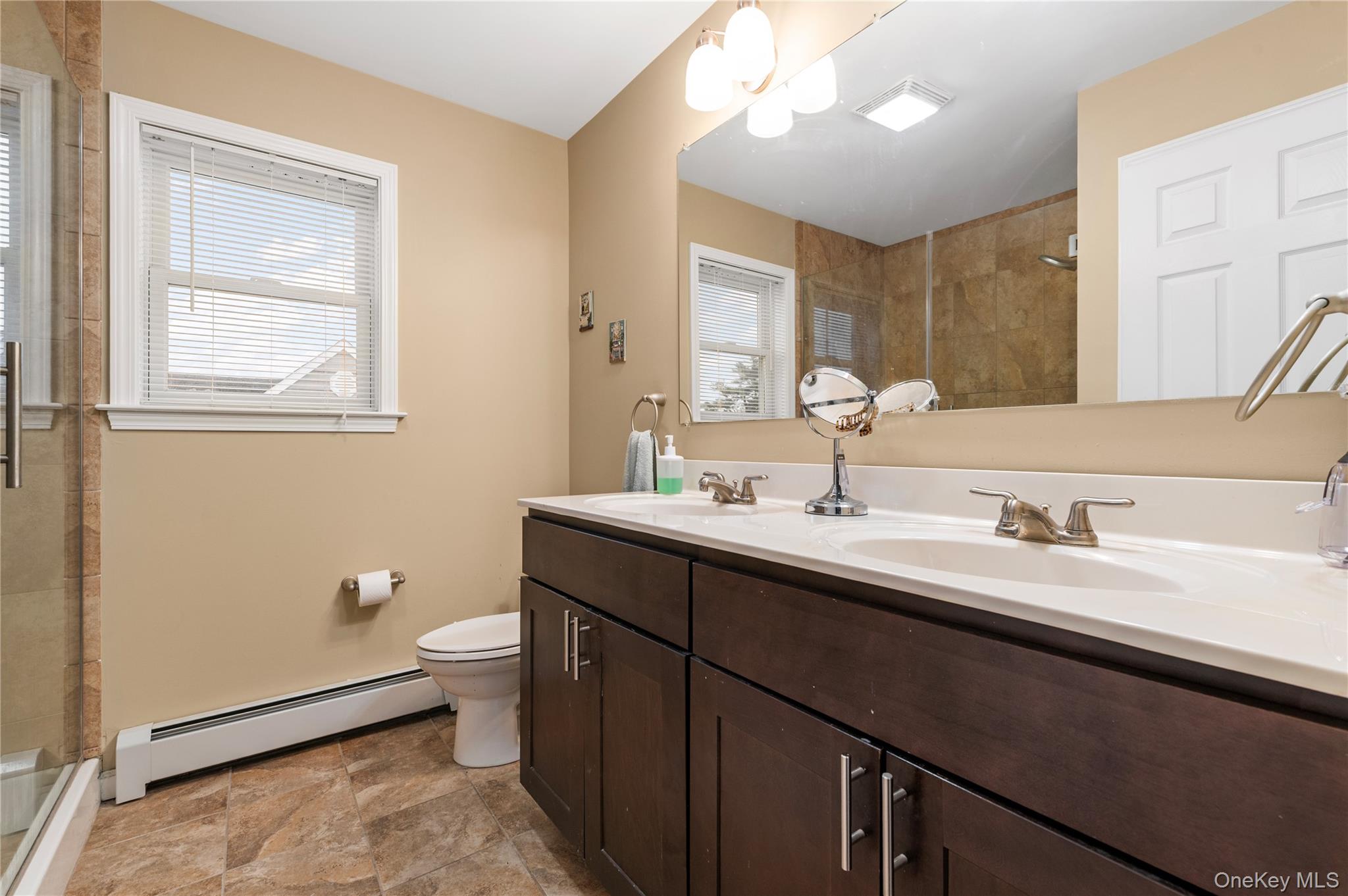 3 Cheshire Road Bethpage, NY 11714 - Photo 14 of 26 a bathroom with a double vanity sink toilet and a mirror