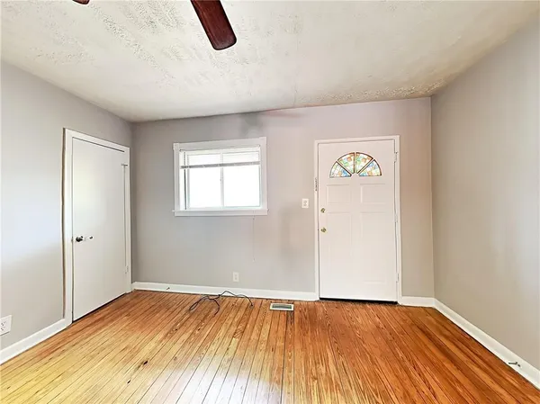 an empty room with wooden floor and windows