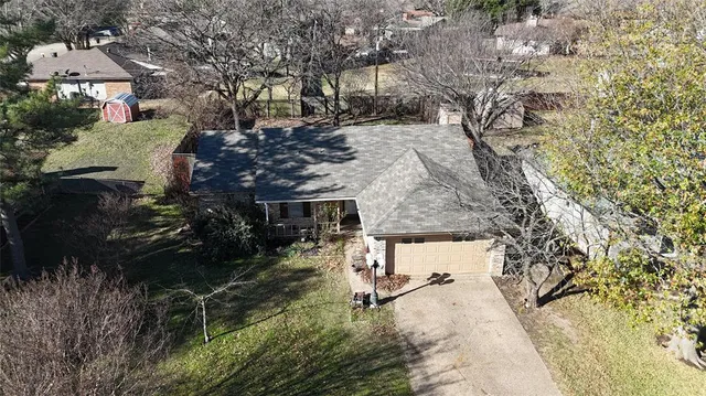 an aerial view of a house with a yard and large tree