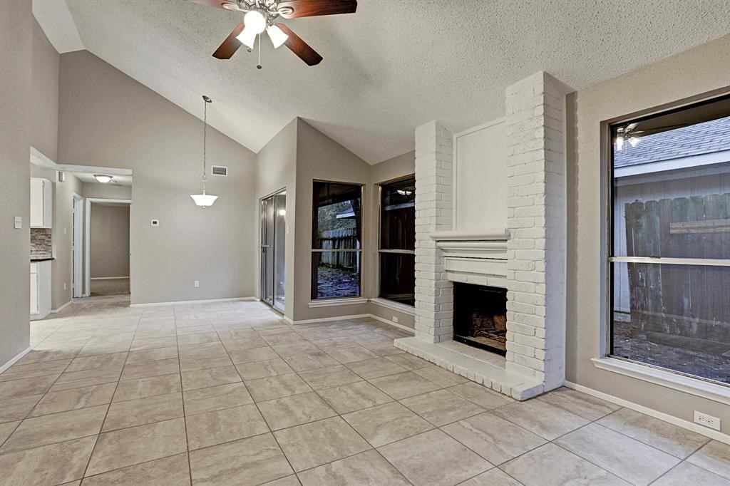 23322 Pebworth Place Spring, TX 77373 - Photo 2 of 10 a view of a livingroom with a fireplace a chandelier a ceiling fan and windows