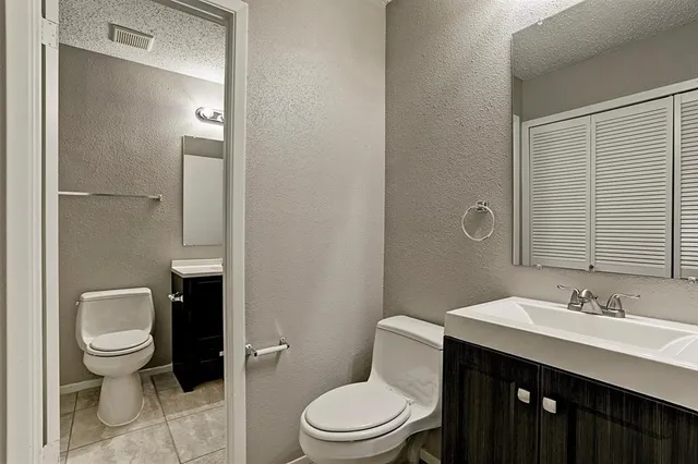 a bathroom with a toilet a sink a mirror and vanity