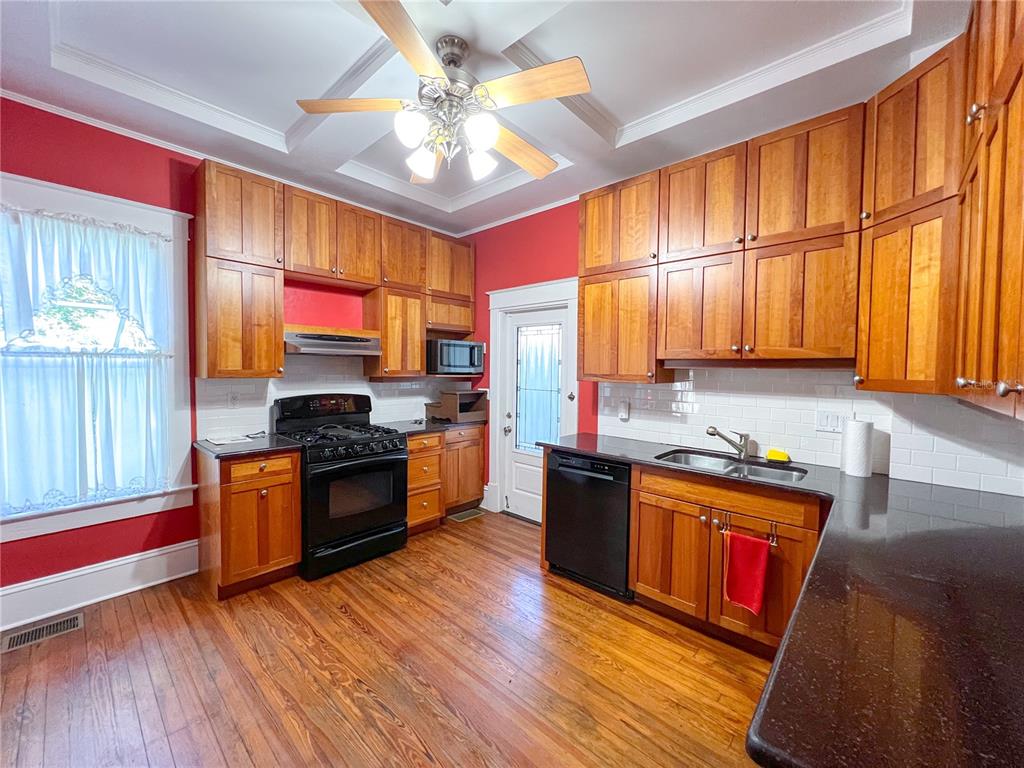 516 Northeast 4 Street Gainesville, FL 32601 - Photo 23 of 57 a kitchen with stainless steel appliances granite countertop wooden floors a stove a sink and a refrigerator