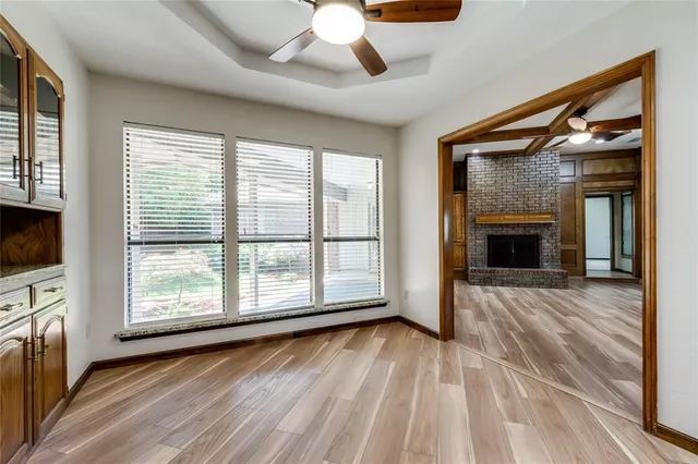 a view of an empty room with wooden floor fireplace and a window