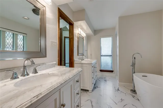 a bathroom with a granite countertop sink mirror vanity bathtub and toilet