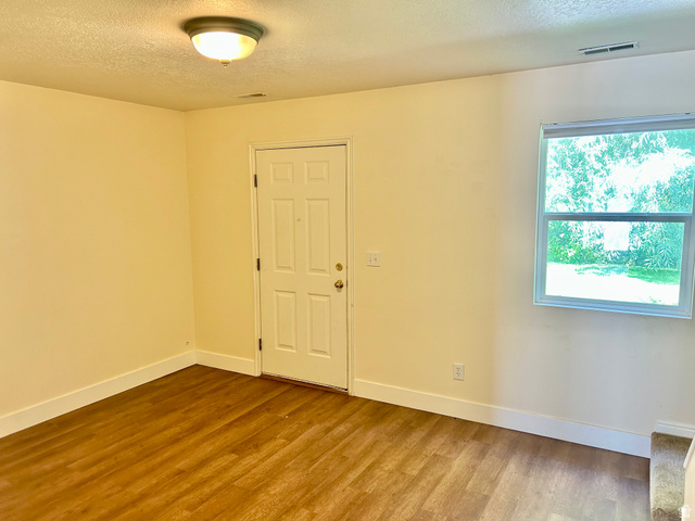 334 West Rodeo Lane South Logan, UT 84321 - Photo 5 of 12 Room featuring wood-finish flooring, a white paneled door with brass hardware, and a window providing natural light