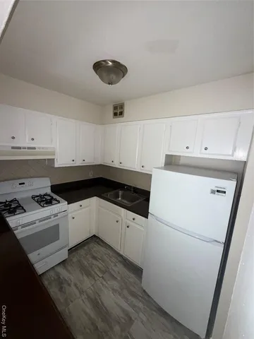 a kitchen with granite countertop white cabinets and white appliances