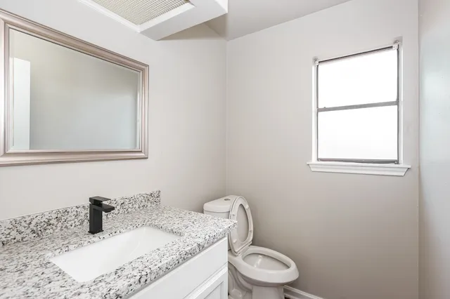 a bathroom with a granite countertop sink mirror vanity and toilet