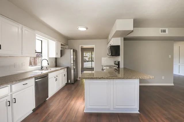 a kitchen with granite countertop a sink cabinets and wooden floor