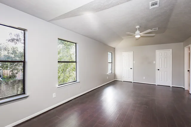 a view of an empty room with a window and wooden floor