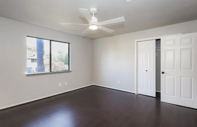 a view of an empty room with wooden floor and a window