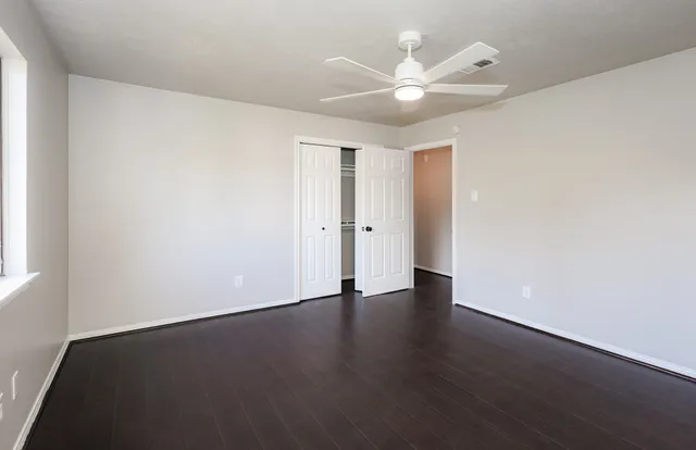 an empty room with wooden floor and a ceiling fan