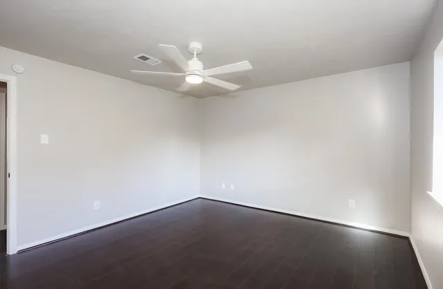an empty room with a ceiling fan and a window