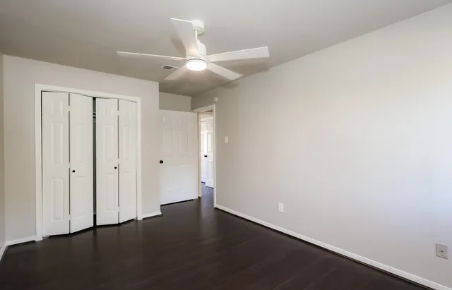 an empty room with wooden floor and fan