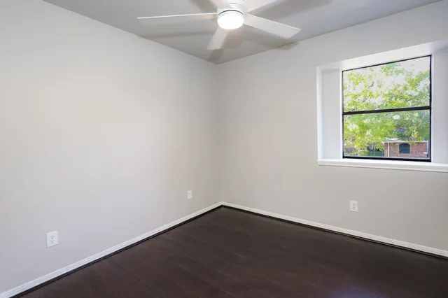 an empty room with a window and a fan