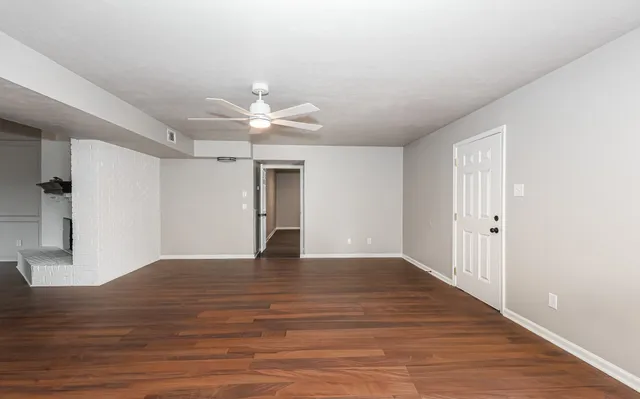 a view of an empty room with wooden floor and a ceiling fan