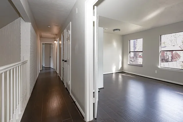 a view of a hallway with wooden floor and windows