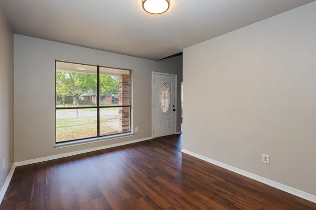 an empty room with wooden floor and windows