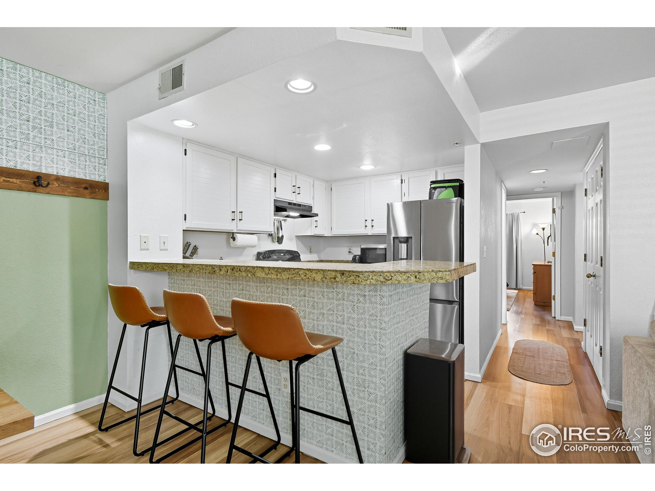 935 Broadway, Unit 104 Boulder, CO 80302 - Photo 7 of 21 a kitchen with stainless steel appliances kitchen island granite countertop a table chairs refrigerator and sink