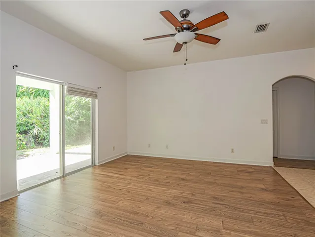 an empty room with wooden floor fan and windows