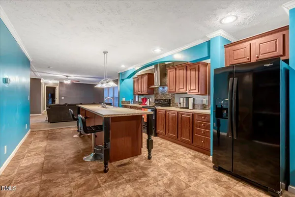 a kitchen with stainless steel appliances kitchen island granite countertop a refrigerator and a stove top oven