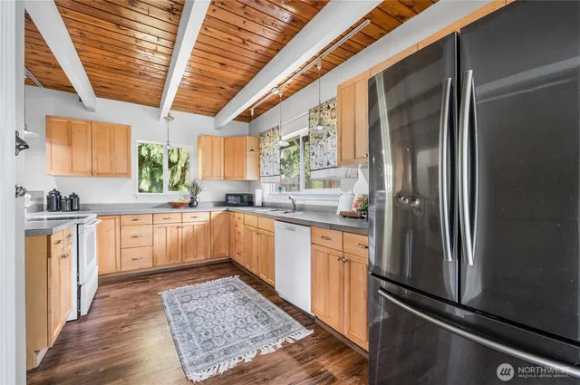 a large kitchen with stainless steel appliances granite countertop a refrigerator a sink dishwasher a stove and white countertops with wooden floor