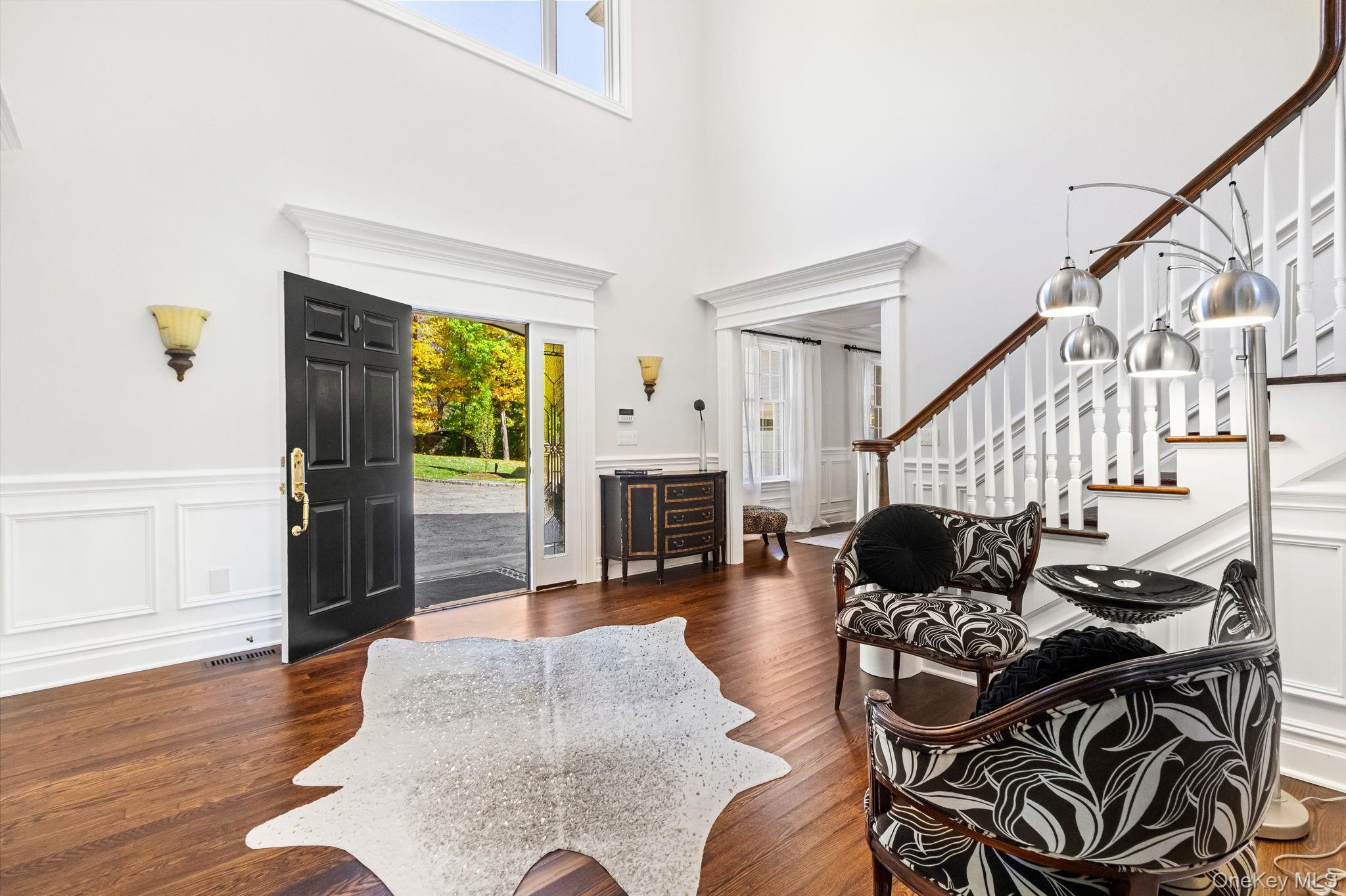 496 Long Ridge Road Bedford, NY 10576 - Photo 3 of 49 Foyer entrance with stairs, wood finished floors, a decorative wall, a towering ceiling, and a wainscoted wall