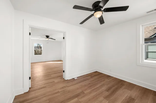 a view of empty room with wooden floor and ceiling fan
