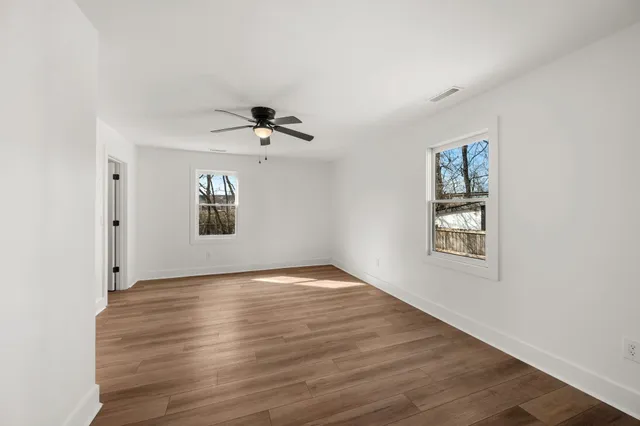 a view of an empty room with a window and wooden floor