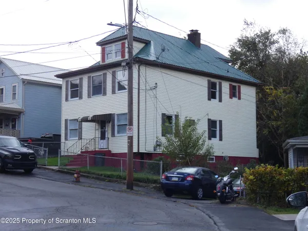 a front view of a house with cars parked