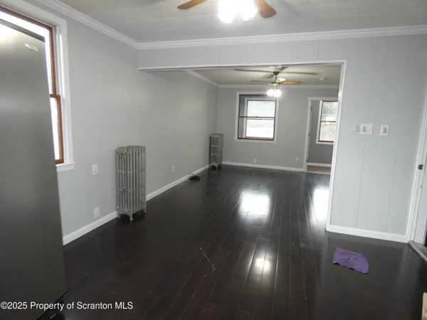 an empty room with wooden floor and windows
