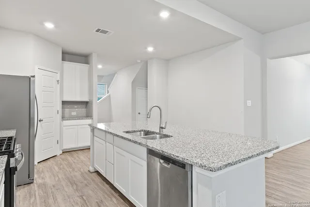 a kitchen with stainless steel appliances granite countertop a sink cabinets and wooden floor