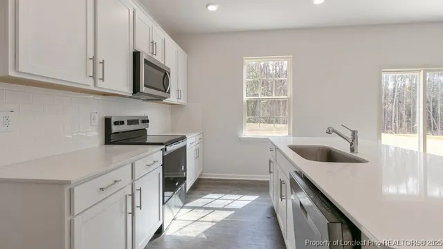 a kitchen with stainless steel appliances granite countertop white cabinets a sink and a stove