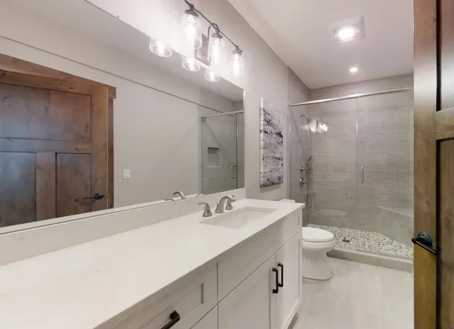 a bathroom with a sink a toilet and shower a mirror