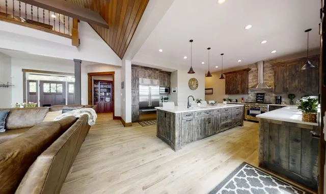 a large kitchen with stainless steel appliances kitchen island granite countertop a large stove a sink dishwasher and white cabinets with wooden floor