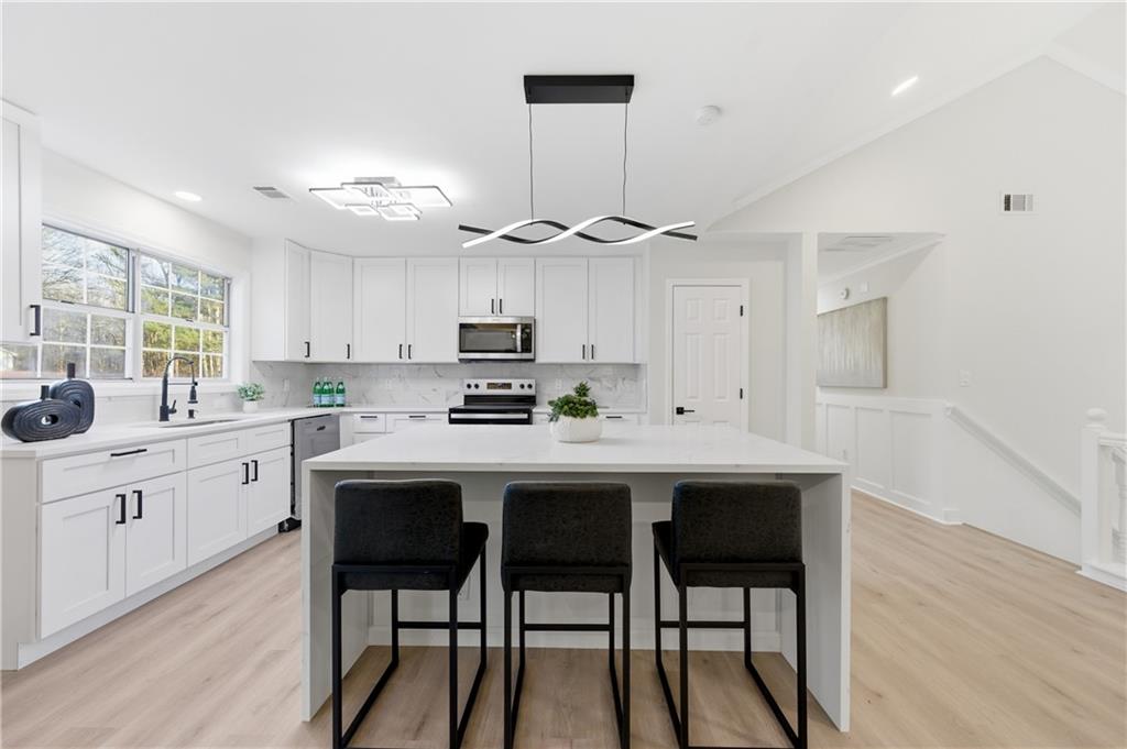 3363 Old Oaks Road Buford, GA 30519 - Photo 9 of 29 a kitchen with stainless steel appliances a table chairs refrigerator and sink