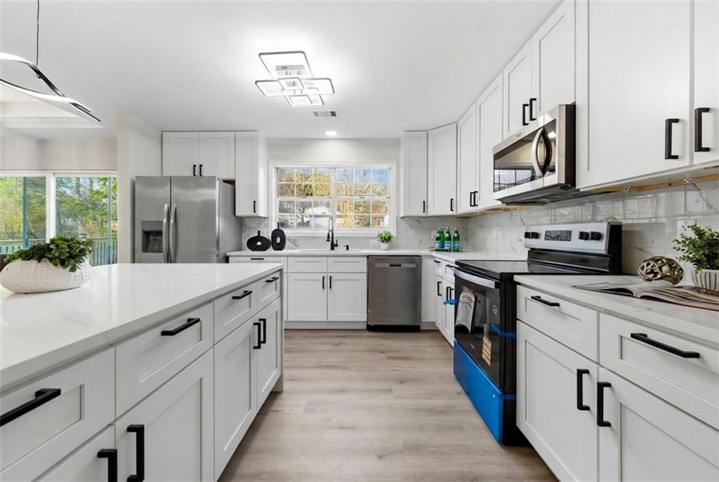 3363 Old Oaks Road Buford, GA 30519 - Photo 10 of 29 a kitchen with stainless steel appliances a sink dishwasher a stove top oven a refrigerator with wooden floor