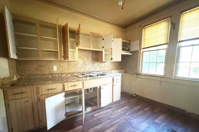 a kitchen with stainless steel appliances granite countertop a stove a sink and white cabinets with wooden floor next to windows