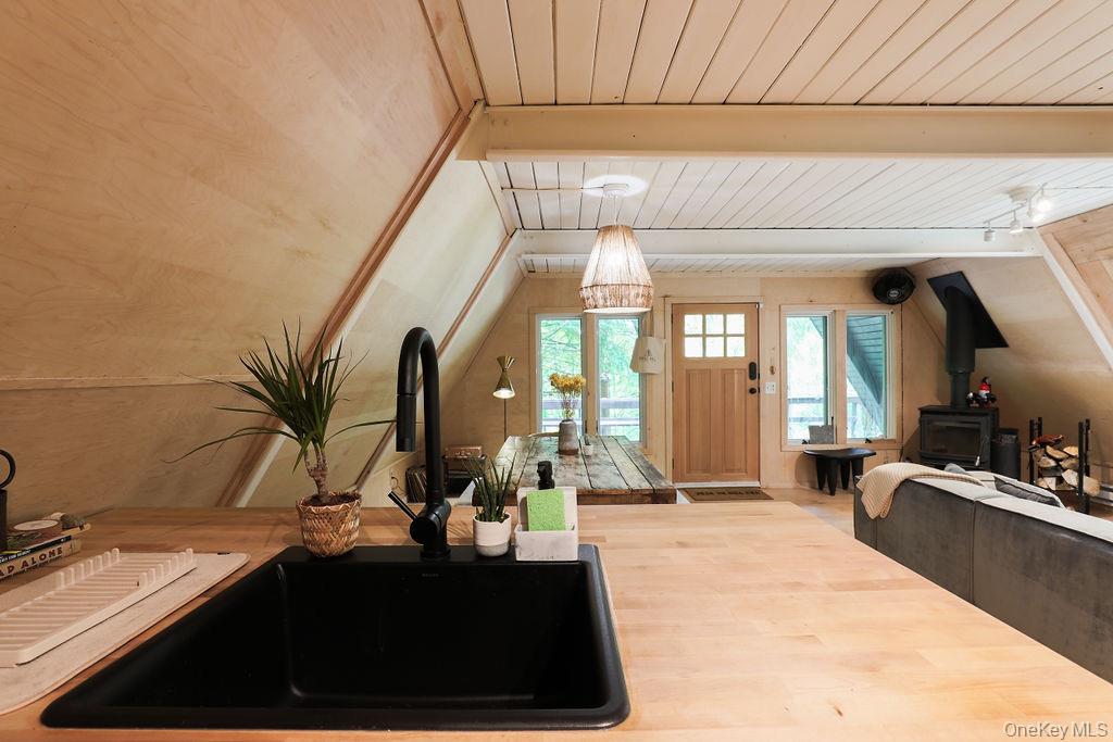 161 Pine Hill Road Shandaken, NY 12410 - Photo 39 of 39 Kitchen featuring a wooden ceiling with exposed beams, pendant lighting, open floor plan, a wood stove, and butcher block counters