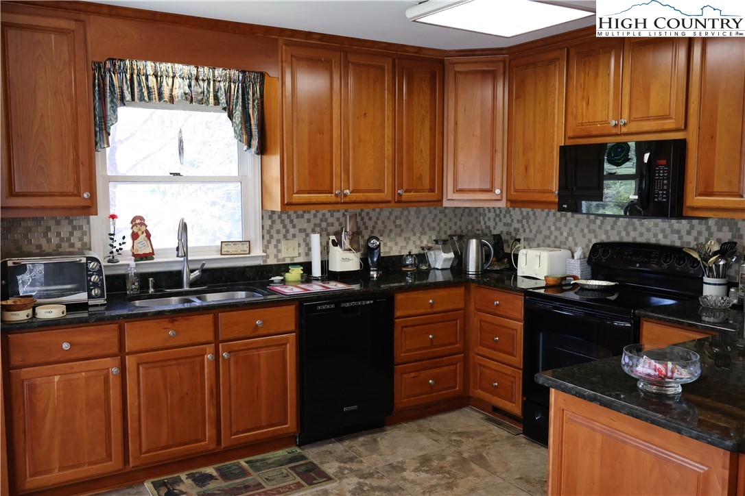 488 Meadow View Road Glade Valley, NC 28627 - Photo 9 of 32 a kitchen with granite countertop wooden cabinets and a stove top oven
