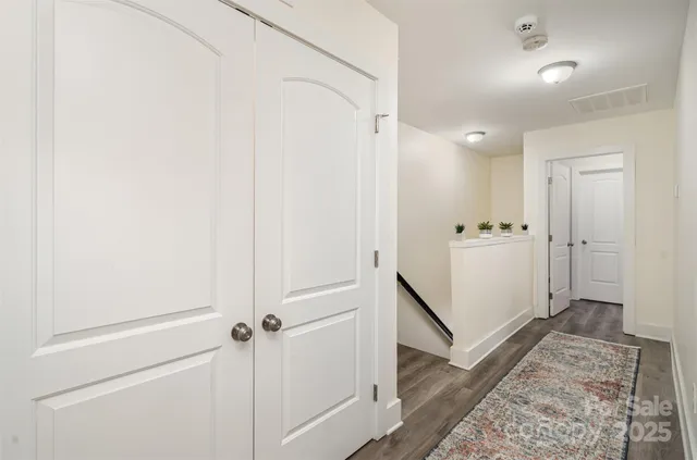 a view of a hallway with white cabinets and wooden floor