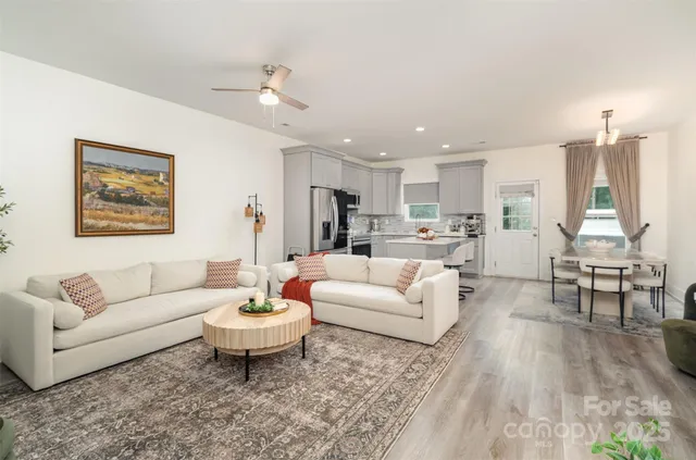 a living room with furniture and a dining table with wooden floor