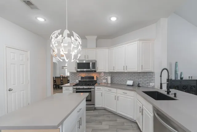 a kitchen with kitchen island granite countertop stainless steel appliances a sink a stove cabinets and a counter top space