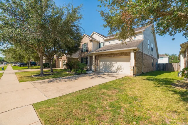 a view of a house with a yard and large tree