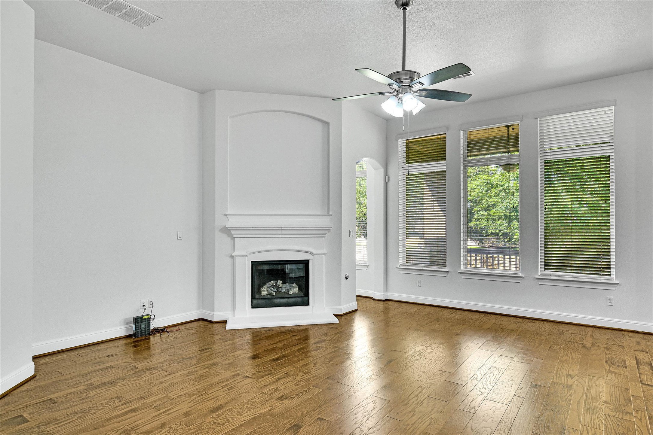 2325 Blended Tree Ranch Drive Leander, TX 78641 - Photo 9 of 35 A refined living space features gleaming hardwood floors and a cozy fireplace with elegant white mantel.