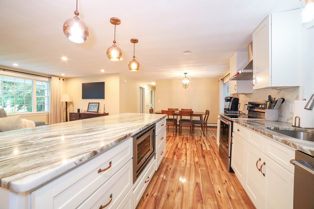 142 Mill Road Chelmsford, MA 01824 - Photo 5 of 34 a large kitchen with kitchen island a large counter space a sink appliances and living room view