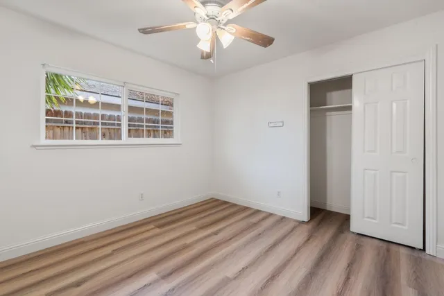 a view of empty room with wooden floor and fan