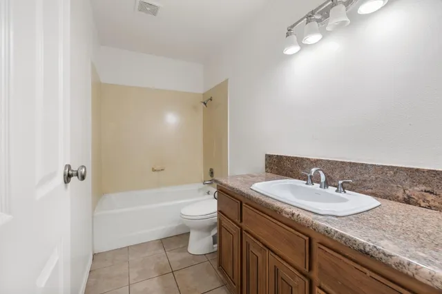 a bathroom with a granite countertop sink a toilet and bathtub