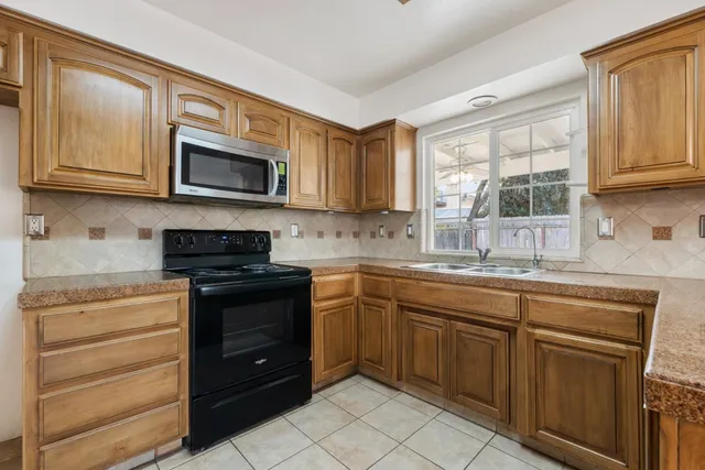 a kitchen with stainless steel appliances granite countertop white cabinets a stove a sink and dishwasher