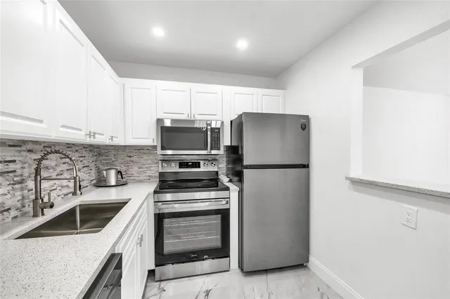 a kitchen with a refrigerator sink and white cabinets
